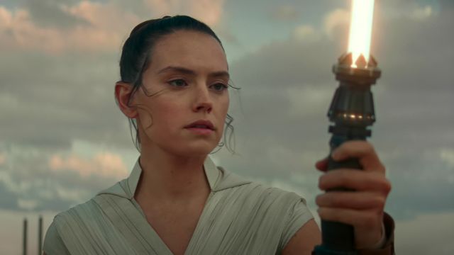 Rey holding her yellow lightsaber up
in front of her, concentrating